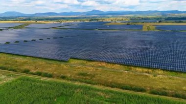 Bölgeye yerleştirilmiş sayısız fotovoltaik hücre. Manzaranın üzerinde bulutlu bir gökyüzü. Hava görünümü.