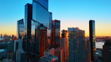 New York 'un muhteşem modern cam gökdelenleri. Güneş, arka planda, suyun üzerinde parıldıyor..