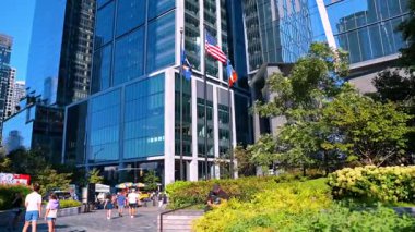 New York, ABD, 5 Ağustos 2025: Cam binaların yanında rüzgarda dalgalanan üç bayrak. New York 'un modern yüksek binalarına düşük açılı perspektiften bakıyorum..