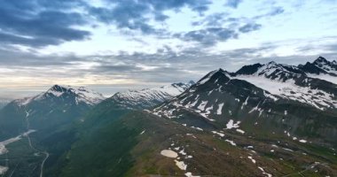 Bazı bölgelerde karla kaplı çarpıcı dağların üzerinde uçmak. Alaska 'nın vahşi doğasında kayalar, Amerika bulutlu gökyüzünün altında.