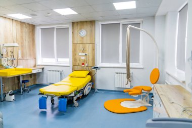 Tıbbi yatağı ve parlak iç yapısı olan modern hastane odası. Sarı yatak ve tıbbi malzemelerle dolu temiz ve iyi donanımlı bir hastane odası.