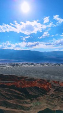 Çıplak kayalar ve dağların arasında geniş bir vadi. Ölüm Vadisi, Kaliforniya, ABD üzerindeki İHA görüntüleri. Dikey video.