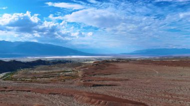 Bulutlu gökyüzünün altında Ölüm Vadisi, Kaliforniya, ABD. Dağ siluetleri arka planda. Hava görünümü.