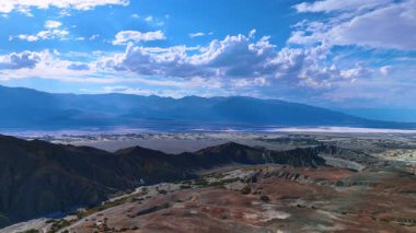 Dağ sırası boyunca otobana daha yakın uçuyor. Geniş vadi, arka planda güneşle parlıyordu. Ölüm Vadisi, Kaliforniya, ABD.