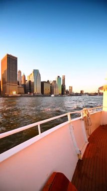 Dalgalar, Doğu Nehri 'nden geçen tekneden geliyor. Gün batımında New York 'un silüeti. Dikey video.
