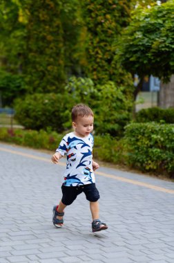 Park yolunda iyi koşular. Yürümeye başlayan çocuk, oyun zamanı boyunca enerji dolu, hızlı adımlar ve odaklanmış bir bakışla yolda koşar..