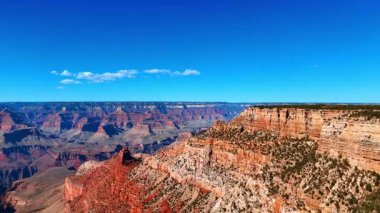 Büyük Büyük Kanyon tepeleri gün ışığında. Canlı gün ışığında yakalanan geniş bir kanyon çıkıntısı manzarası. Sahne dramatik kaya oluşumlarını ve derinliği vurguluyor..
