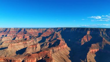Büyük Kanyon 'un güneşli kırmızı kaya duvarları. Güneş ışığı Büyük Kanyon 'un dik kırmızı kaya duvarlarını aydınlatır. Gölgeler arazinin derinliğini ve dokusunu vurgular.