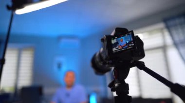 Tripodun üzerindeki kamera ekranda gösterilen bir adamın videosunu çekiyor. Düşük açı. Sıhhiye bir blog için video hazırlıyor. Seçici odak.