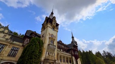 Romanya 'nın Prahova Eyaleti' ndeki güzel Peles Kalesi 'nin saat kulesine yaklaşıyoruz. Düşük açı. Arkaplanda mavi gökyüzünde gri bulut.