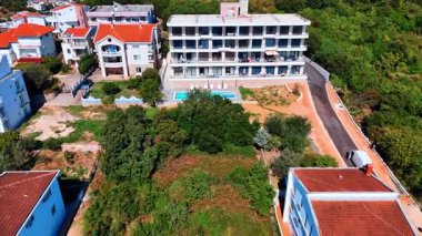 Önünde yüzme havuzu olan bir otel odasına daha yakın uçmak. Binanın çevresi yemyeşil. Karadağ. Hava görünümü.