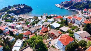 Adriyatik Denizi kıyısındaki güzel körfezden uzakta. Karadağ 'daki dağ yamacını yoğun bir şekilde kapsayan birden fazla evin üzerinden uçuyor.