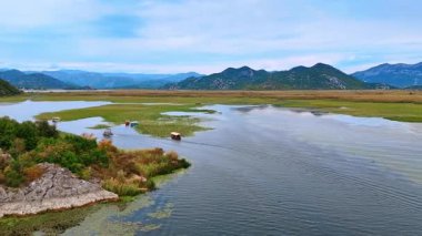 Barakalarla kaplı birkaç tekne otlarla kaplı bir su yatında. Manzarayı çevreleyen güzel dağlar. Hava görünümü.