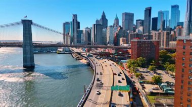 Doğu Nehri suları boyunca otobanlarda gündüz trafiği. Brooklyn Köprüsü ve Manhattan ufuk çizgisinde görünüm.
