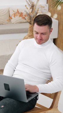 Dizüstü bilgisayarla çalışan çalışkan erkek girişimci koltukta oturuyor. Adam aletini kapatıyor, koltuğa uzanıyor ve nihayet dinleniyor. Üst Manzara. Dikey video