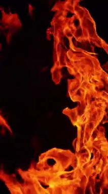 Havada dönen sıcak alevler. Karanlıkta uzun şenlik ateşi yanıyor. Kapatın. Dikey video