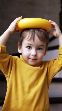 Sevimli beyaz bebek piramit taşını kafasına koyuyor. Oyuncak yere düşer ve çocuk mutlu bir şekilde gülümser. Dikey video