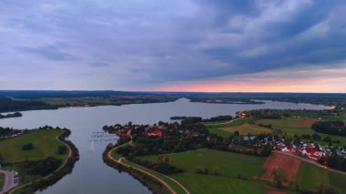 Büyük göl havzasında gün batımı. Sıcak gün batımı ışığı göl boyunca yayılıyor ve kıvrımlı kıyı şeridi boyunca