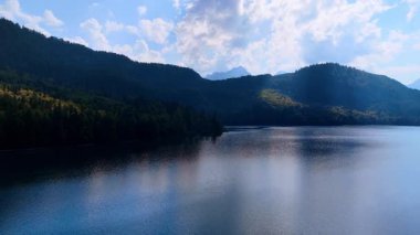 Dağ gölgelerinin altındaki sakin göl. Huzurlu göl dağlardaki tepeleri yansıtıyor..