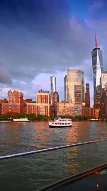 New York 'un ufuk çizgisine ve Doğu Nehri' nden geçen yolcu gemisinden gelen teknelere bakın. Arka planda dramatik bulutlar gökyüzünü kaplıyor. Dikey video.