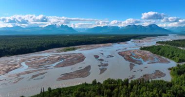 Uçsuz bucaksız ormanlık vadideki güzel nehir deltası. Kümülüs tüylü bulutlar sersemletici dağ sırasının üzerinde gökyüzünde. Hava görüntüsü. Alaska, ABD.