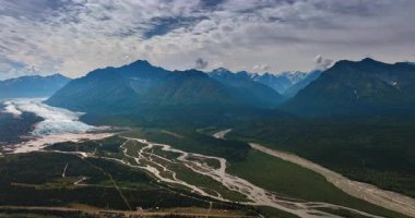 Buzul vadideki parkı dallanan bir nehre çeviriyor. Bulutlar çarpıcı kayaların üzerindeki gökyüzünü kaplıyor. Alaska, ABD.