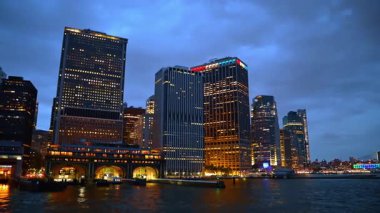 Night skyline of New York against cloudy sky. Low angle view on the high-rise buildings of metropolis with light on in the windows.