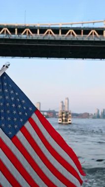 River cruise by the boat with American flag. The Manhattan Bridge from low angle view. New York skyline at backdrop. Vertical video.