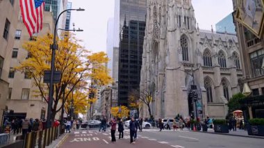 New York, USA, 6 November 2025: People walk and take pictures in the street of New York, USA. Low angle view at St. Patrick's Cathedral. Autumn day in the city.