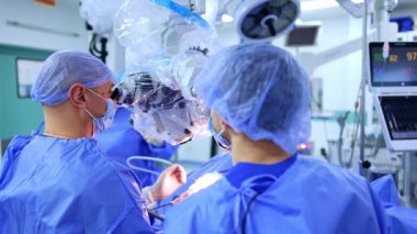 Kyiv, Ukrayna, 2 Ağustos 2025: Cerrahi mikroskop altında beyin cerrahları. İki beyin cerrahı, parlak bir ameliyathanede kapalı bir cerrahi mikroskop kullanarak ameliyat eder..