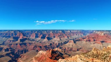 Deep canyon cliffs under blue sky. Tall cliffs stretch across the horizon beneath a clear blue sky.