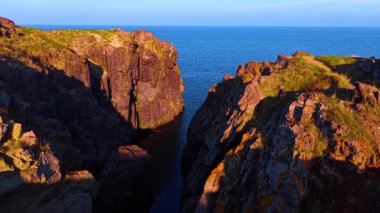 Deniz ya da okyanus kıyısındaki güneşli kayalar arasındaki görüntüler. Uçsuz bucaksız mavi deniz manzarasını gözler önüne seriyor..