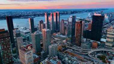 New York, ABD, 8 Ağustos 2025: Günbatımında New York 'un işlek yollarında bir nakliye aracı hareket ediyor. İHA görüntüleri şehre iniyor. Arkaplanda nehir manzarası.