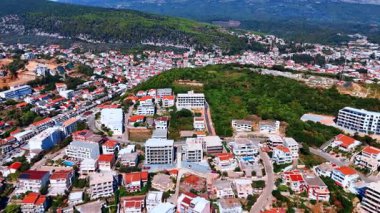 Sunny scenery of urban landscape scattered on the rocky slopes. Drone footage over Ulcinj, Montenegro.