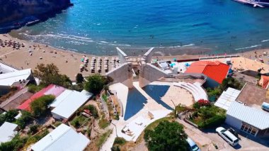 Distancing from the monument on the shore of the sea in Ulcinj, Montenegro. Rocky coast of the Adriatic Sea on sunny day from drone.