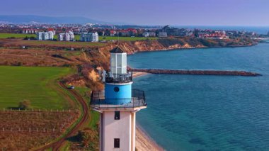 Footage at the top of the lighthouse located at the sea shore. Agriculture fields and cityscape at backdrop.