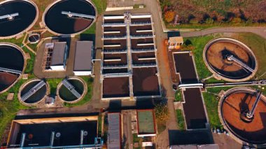 Flight over the territory of modern sewage treatment plant. Flock of birds flies over the circle and rectangular reservoirs with water.