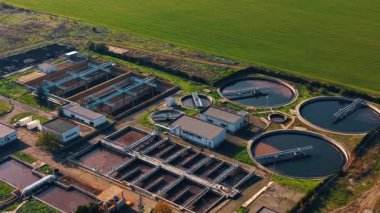 Footage over the modern plant for waste water management. Green field and coast of the waterscape at backdrop.