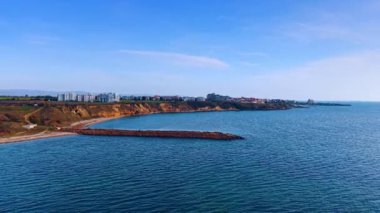 Long pier at the blue waterscape. Revealing view on the cityscape located on the sea shore.