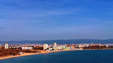 Slow flight over the blue waterscape approaching the sunny sandy beachline. Cityscape of beautiful Nessebar, Bulgaria from drone.