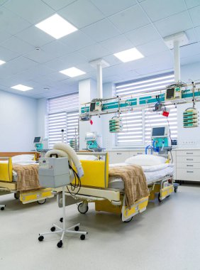 Intensive care beds and respirator unit. Row of intensive therapy beds with respiratory machines and infusion pumps in bright modern hospital ward.