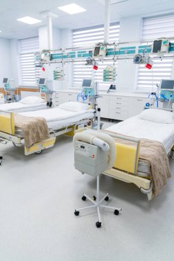 Resuscitation room with medical devices. Prepared resuscitation intensive care room with hospital beds, blankets and various monitoring and breathing devices.