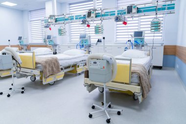 Empty intensive care beds in ward. Bright ICU room with several prepared hospital beds and equipment