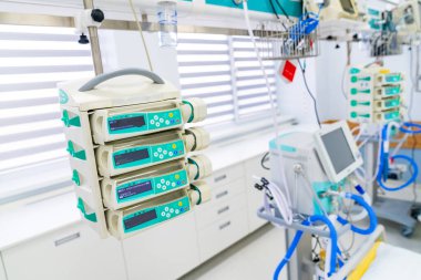 Infusion pumps hanging over hospital bed. Multiple syringe pumps mounted on rail in intensive therapy ward