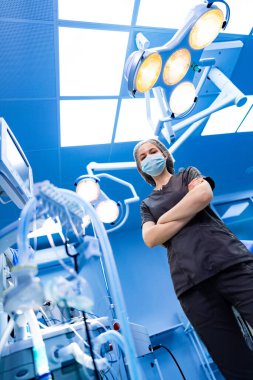 Hemşire ameliyat ışıkları altında duruyor. Ameliyathanede parlak ameliyat ışıkları altında güvenle duran hemşire..