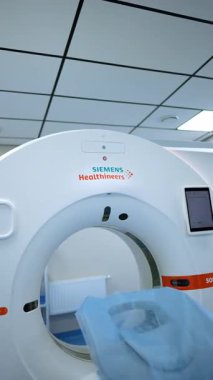 Kyiv, Ukraine, 2 August 2025: CT scanner table with a blue protective cover. The vertical shot focuses on the patient couch entering the machine's gantry.