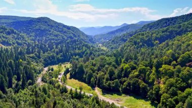 Misty clouds drifting over the mountain spine. The weather creates a moody atmosphere around the sharp stone formations.