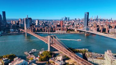 Motorboat moves among the famous bridges of New York, USA. Aerial perspective eon the East River and sunny cityscape.