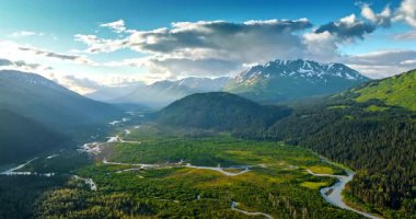 Breath-taking valley crossed by the wavy river. Spectacular mountains surround the picturesque scenery. Wilderness of Alaska. Drone footage.