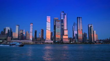 New York, USA, 28 August 2025: Modern motor boat carrying people moves quickly by the blue waterscape of the East River. Stunning skyscrapers and high-rises of Manhattan reflect the soft light of setting sun. View from the riverscape.